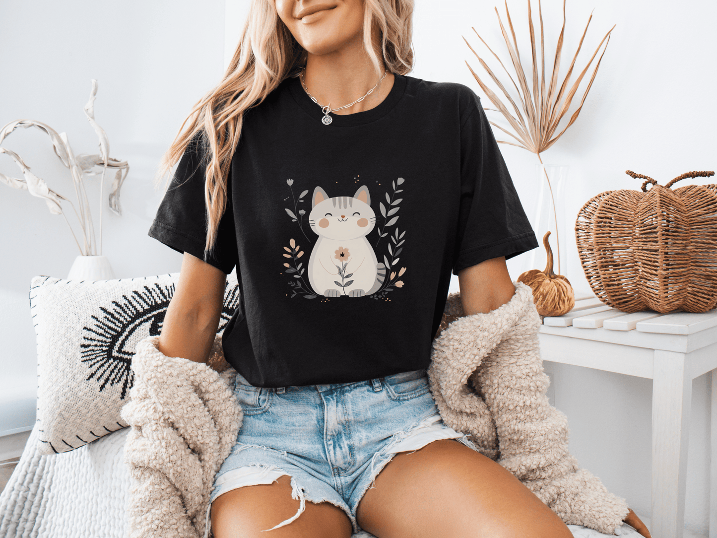 Woman wearing a black t-shirt with a cute floral cat illustration, sitting casually