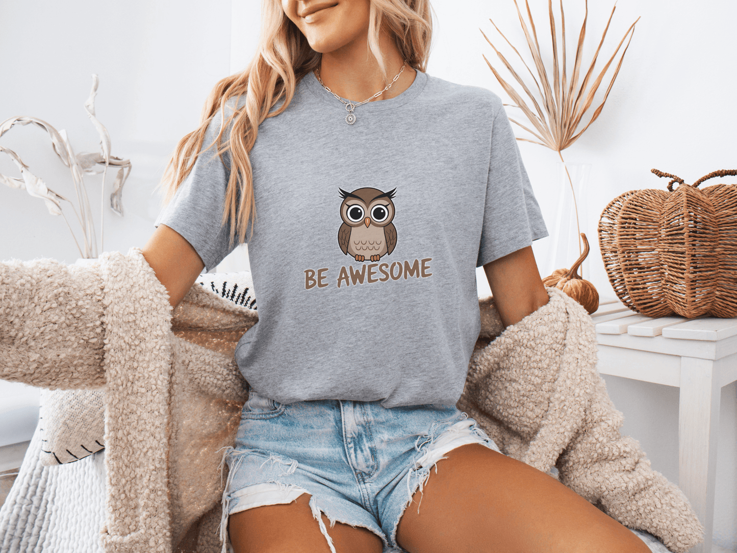 Woman wearing a grey t-shirt with a cute owl and the phrase “Be Awesome”