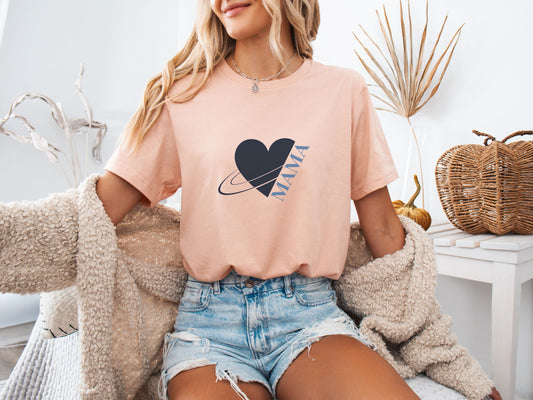 Woman wearing heather peach MAMA shirt with heart and planet illustration