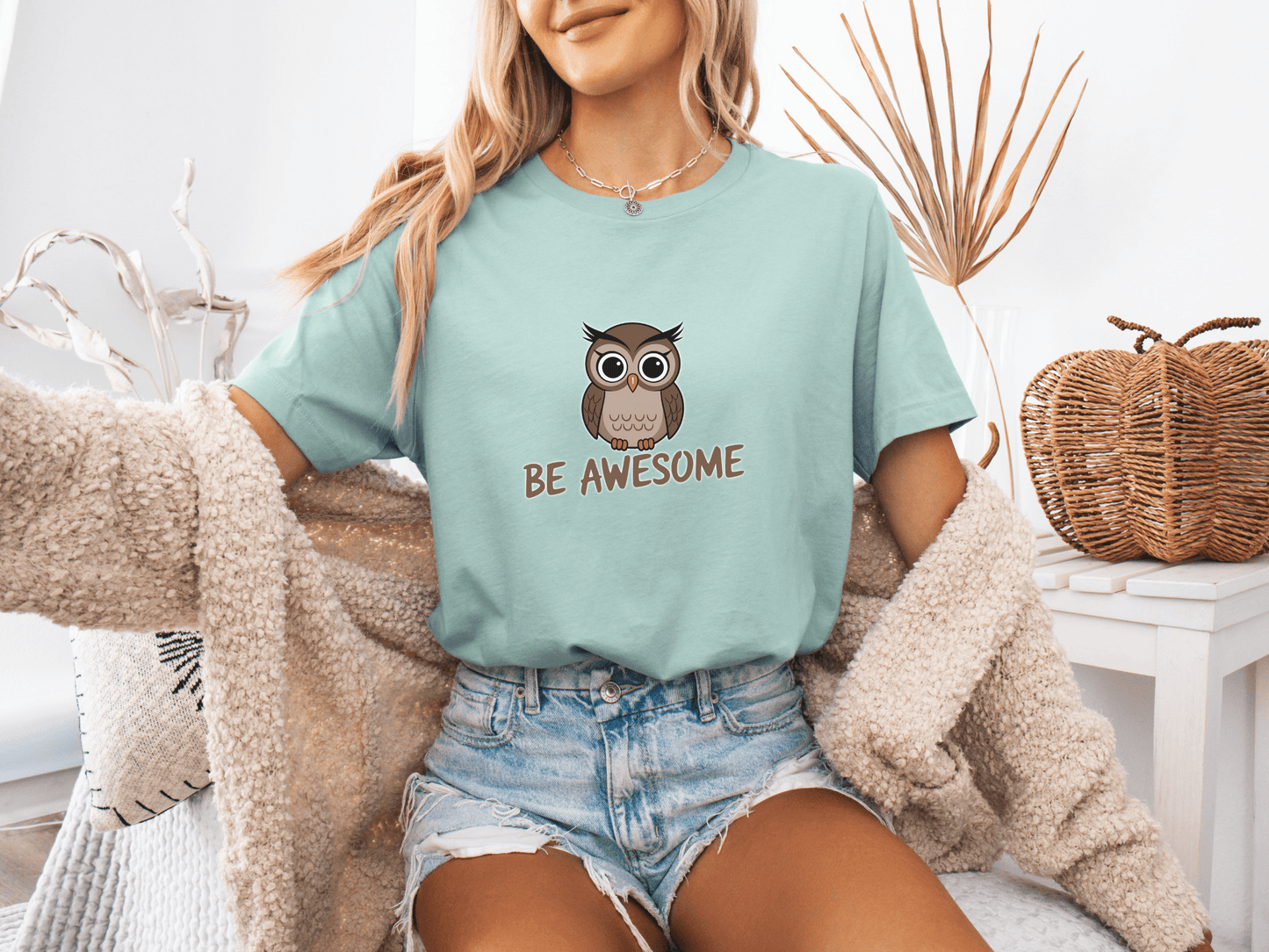 Woman wearing a dusty blue t-shirt with a cute owl and the phrase “Be Awesome”