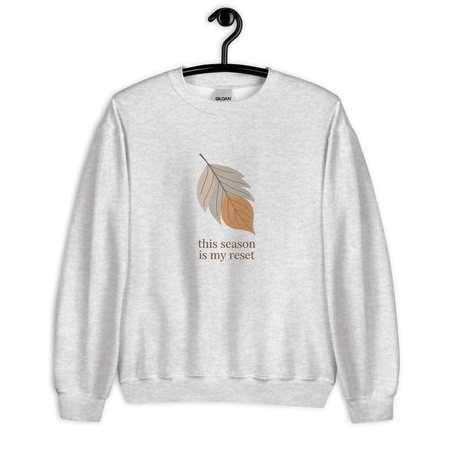 Gray sweatshirt with leaf graphic and text 'this season is my reset' on a hanger against a white background