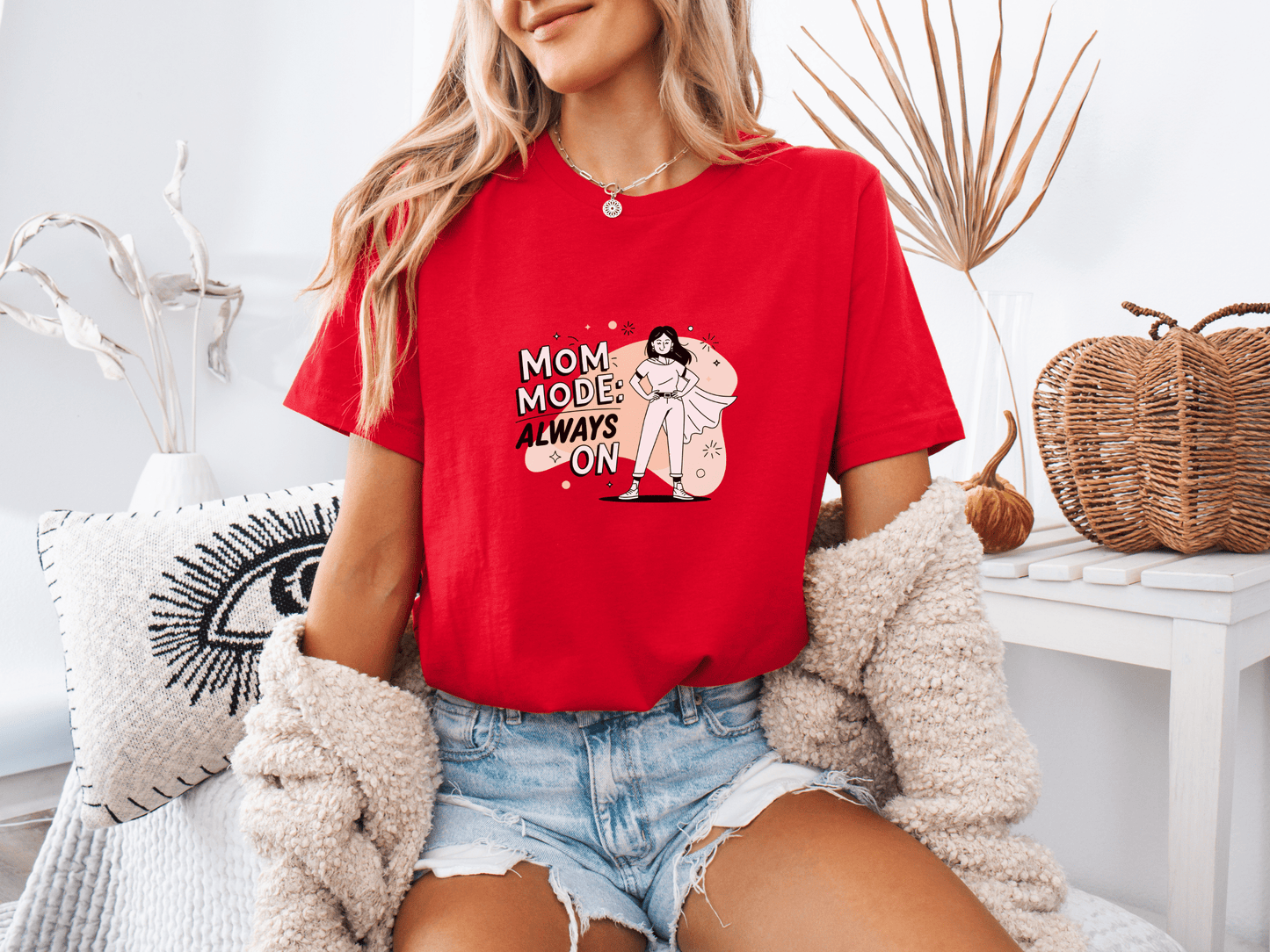Woman wearing red “Mom Mode Always On” graphic t-shirt, sitting casually.