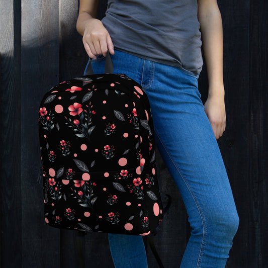 Woman holding floral black backpack with red flowers and polka dots