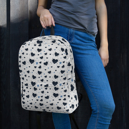 Woman wearing white backpack with all-over navy heart and star pattern, front pocket and visible inside pocket