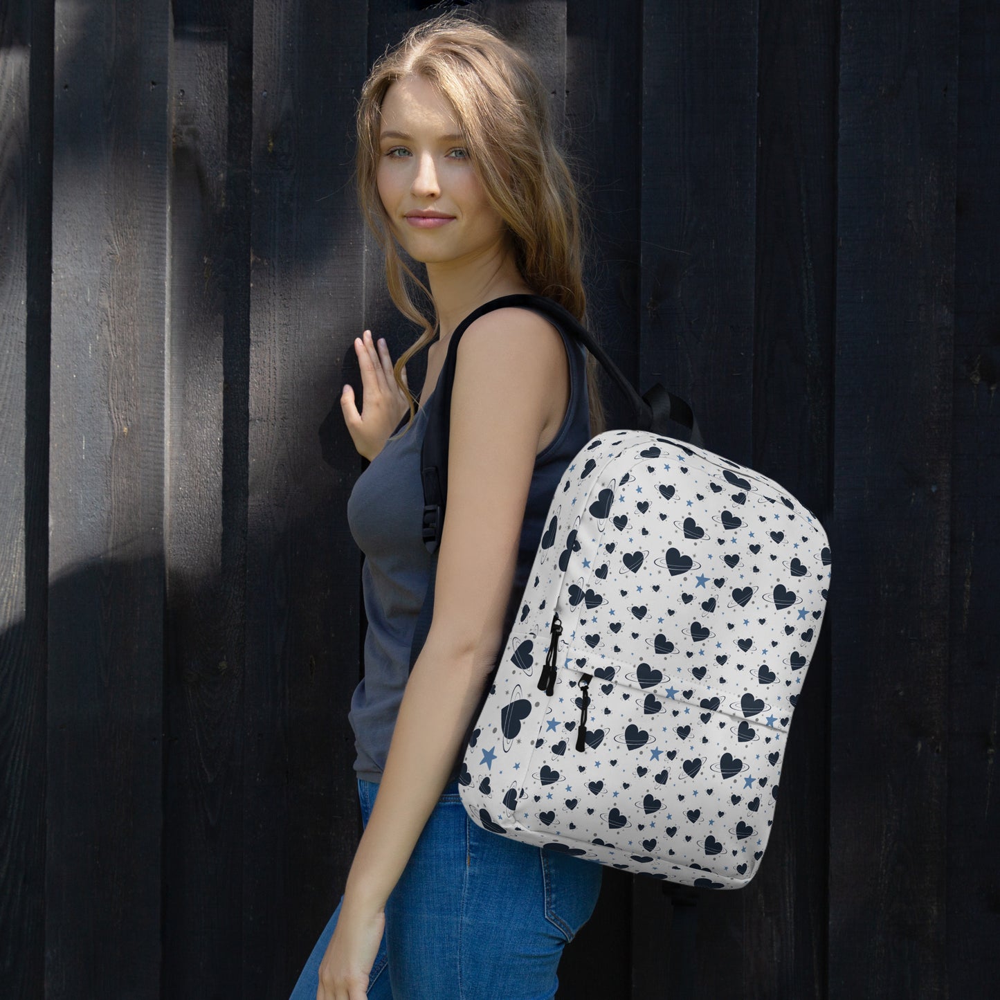Woman wearing white backpack with all-over navy heart and star pattern, front pocket and visible inside pocket label