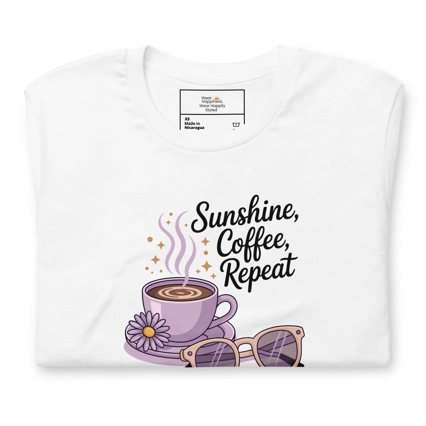 Folded white t-shirt showing close-up of “Sunshine, Coffee, Repeat” graphic with pastel latte art, sunglasses and sparkles