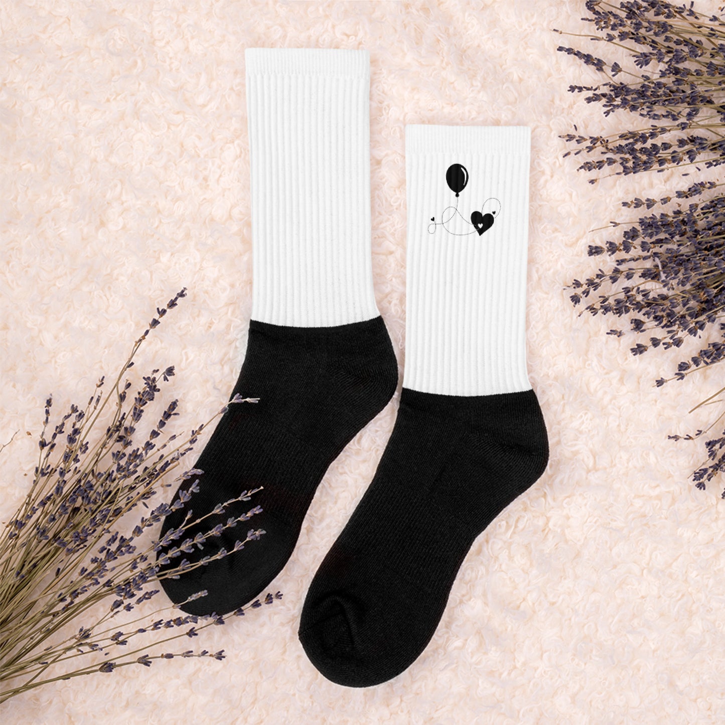 Cozy black and white socks with heart and balloon design – flat lay on soft beige background with lavender sprigs