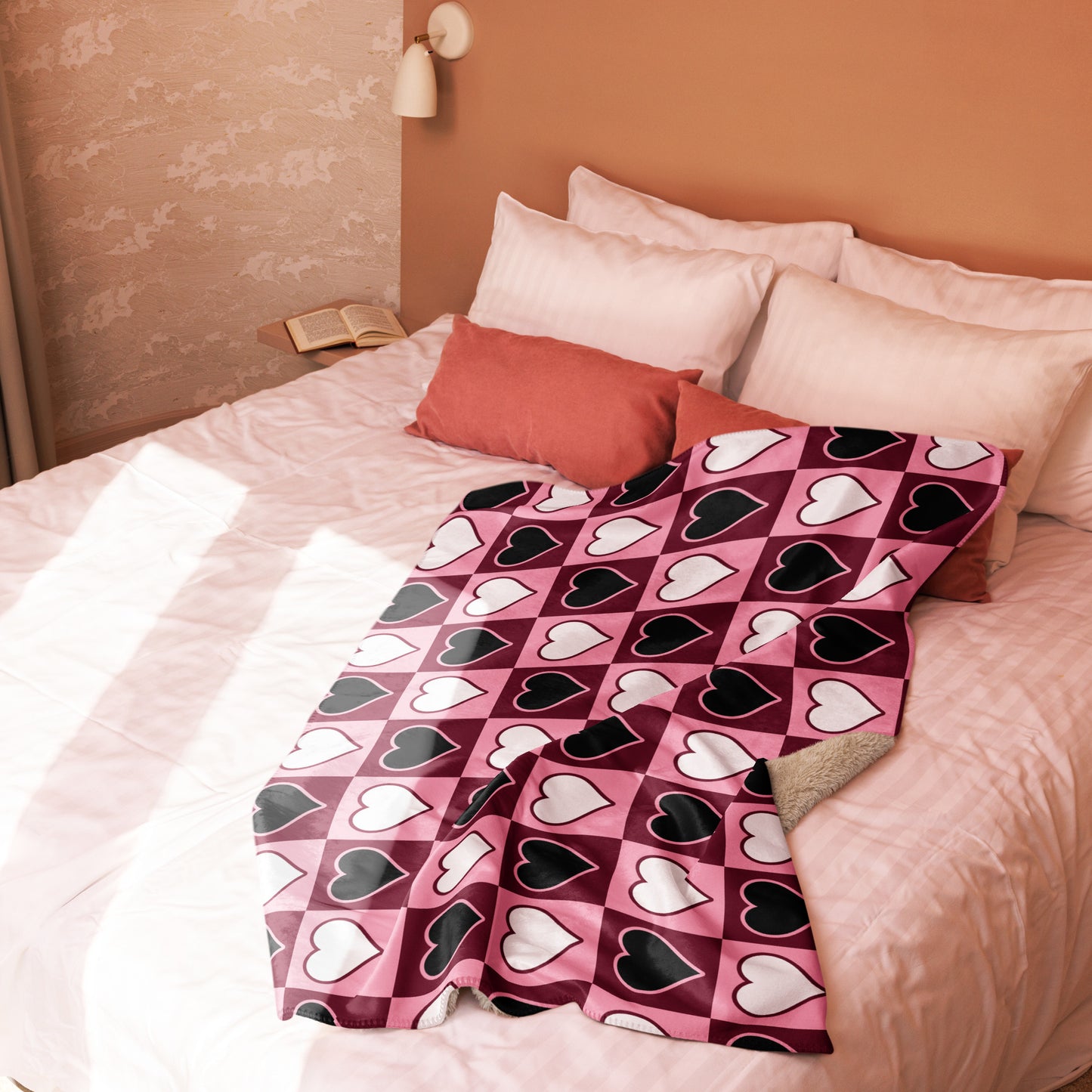 Pink, white, and black heart pattern throw blanket draped casually on bed corner