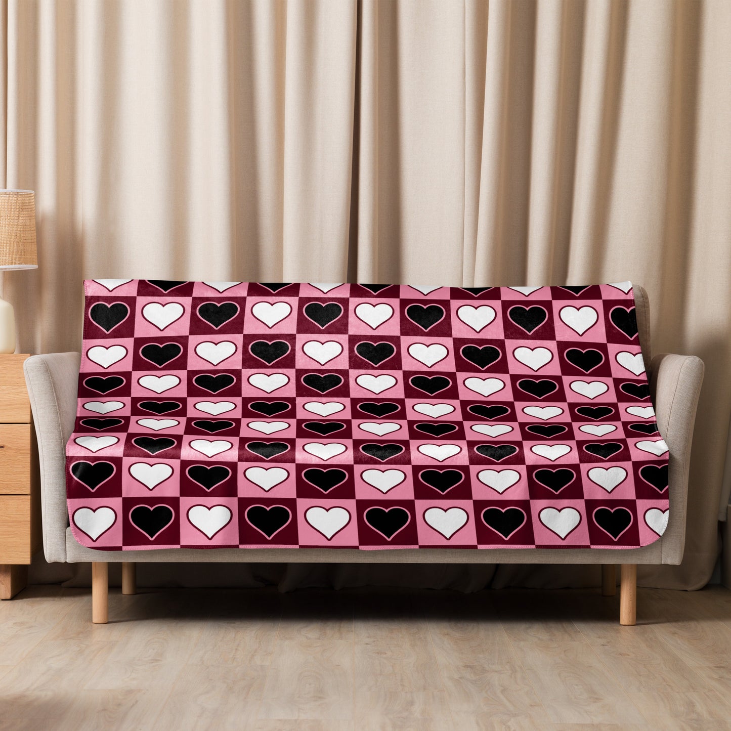 Medium-size pink sherpa blanket with cute heart design styled on a modern sofa