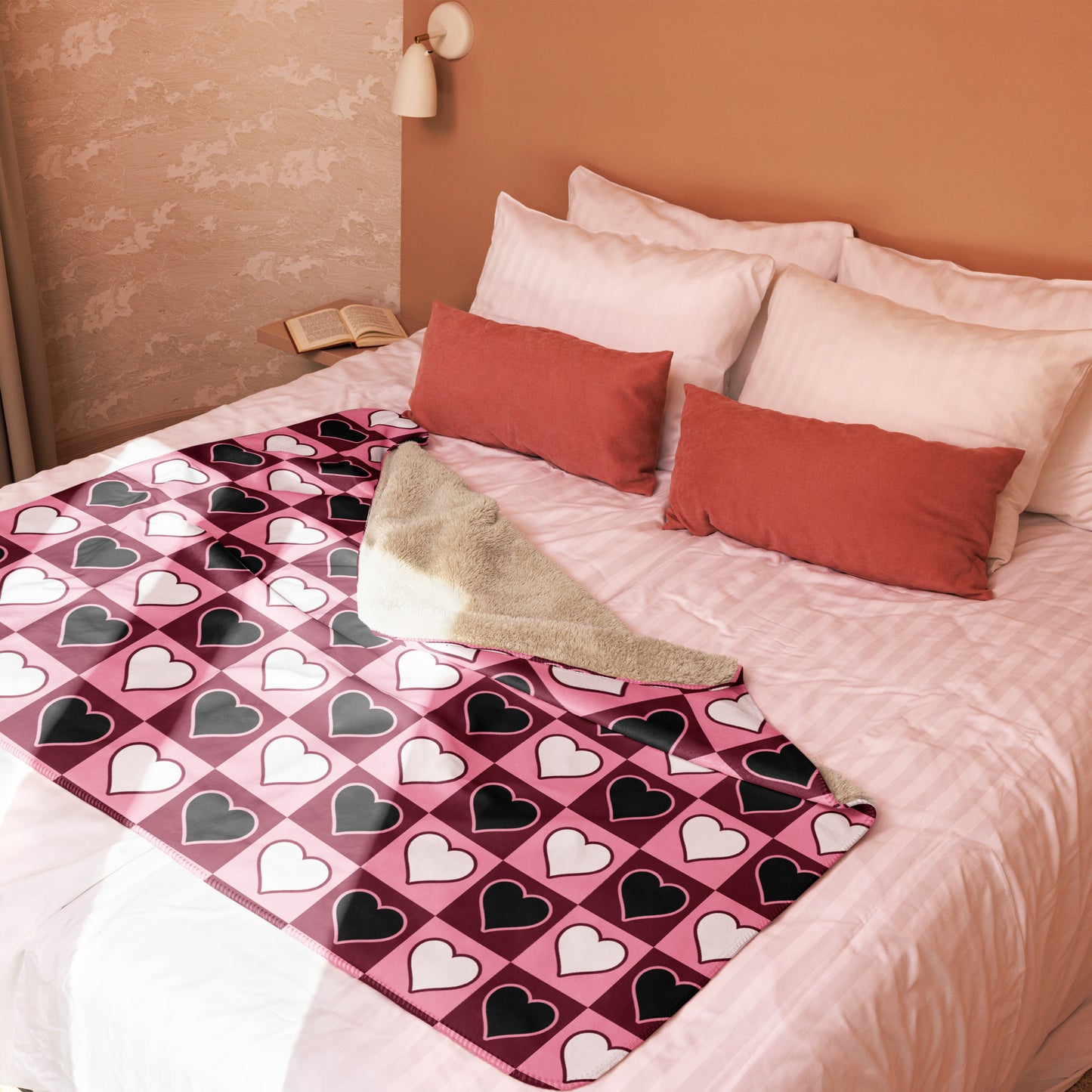 Heart pattern sherpa blanket in pink, white, and black, styled on a neatly made bed with a cozy folded corner