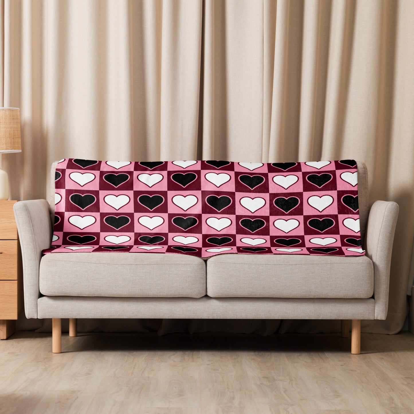 Small heart pattern sherpa blanket draped over a neutral beige sofa