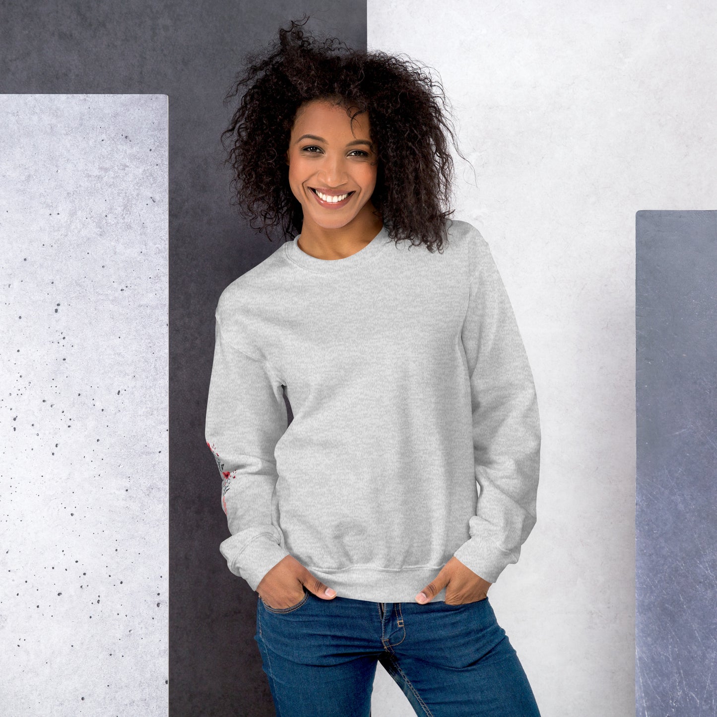 Smiling woman wearing ash sweatshirt with floral design detail on the sleeve - front view