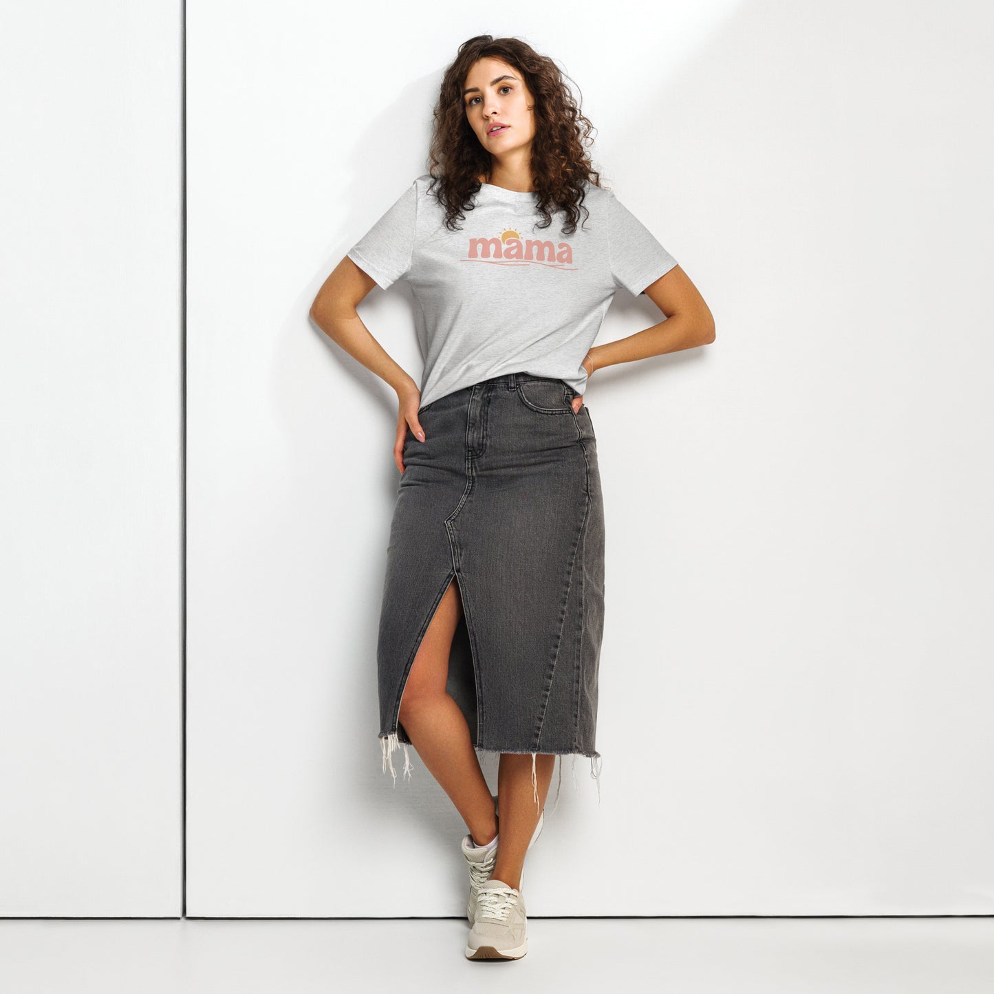 Woman wearing grey ‘mama’ t-shirt with pastel sun design, styled with denim skirt, standing against white wall