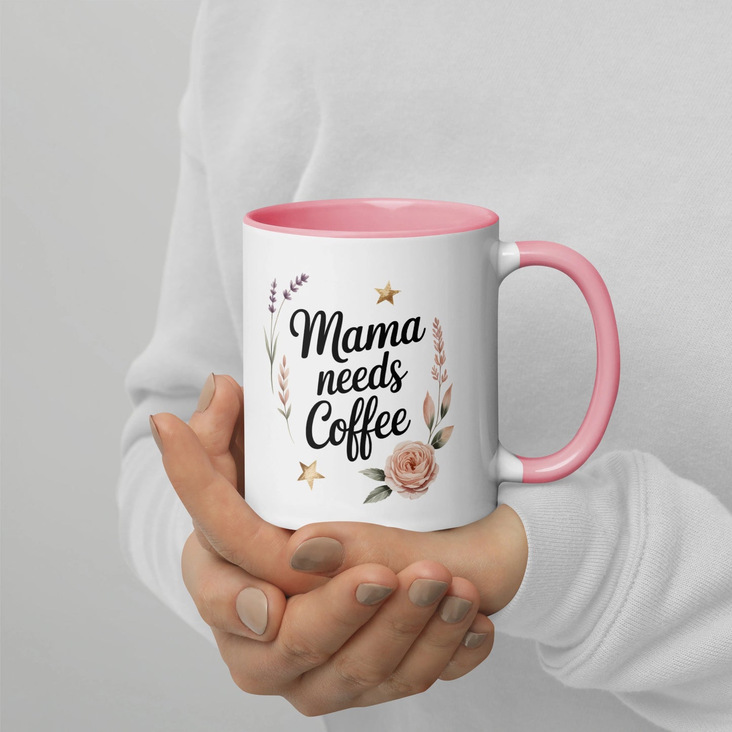 Woman holding โMama Needs Coffeeโ mug with pastel design, cozy lifestyle scene.