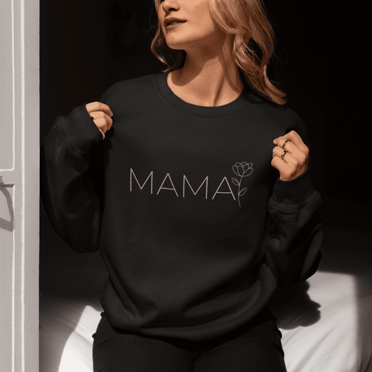 Woman wearing a black minimalist MAMA sweatshirt with floral design, sitting by the window and enjoying the sunlight