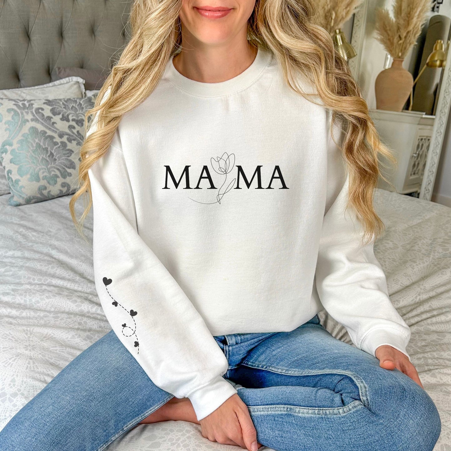 Woman wearing white "MAMA" sweatshirt with floral design and heart balloon sleeve print