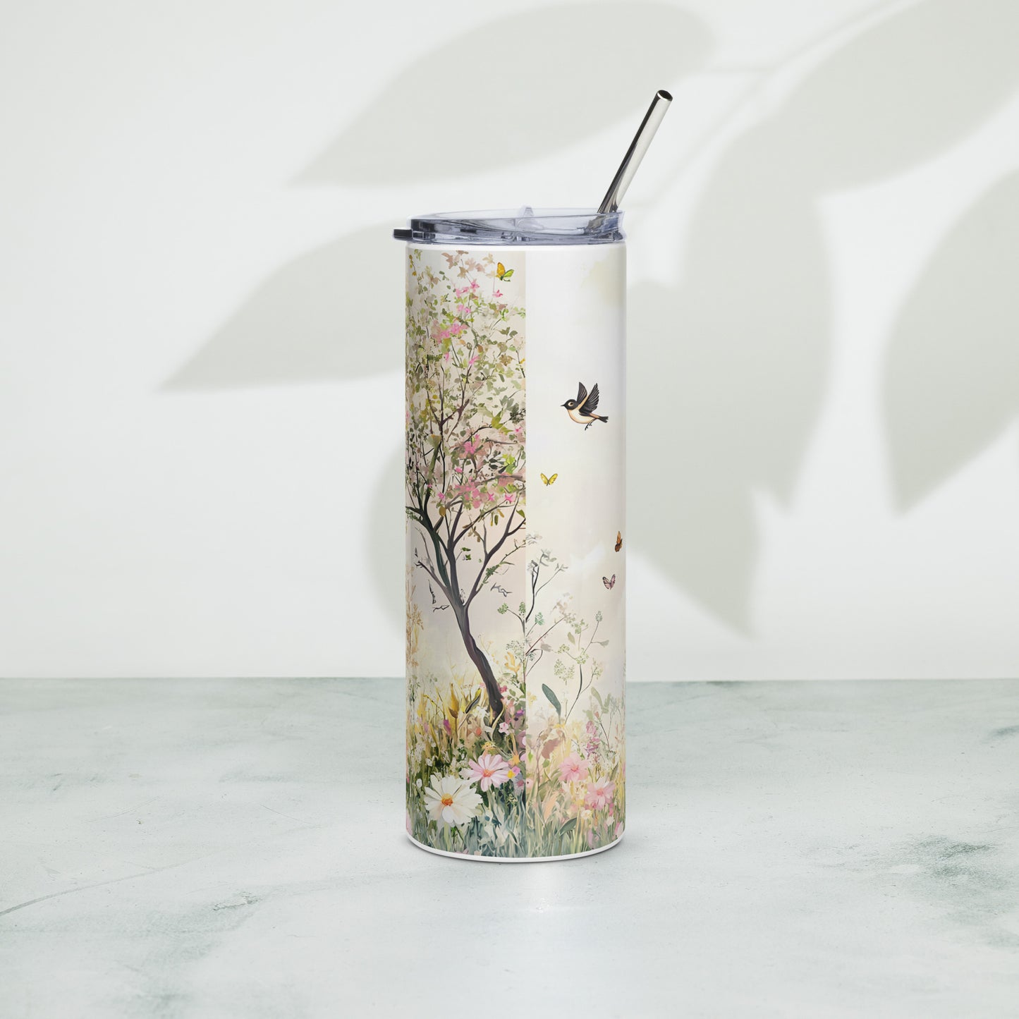 Tall pastel floral tumbler with a tree and birds, standing upright on a minimal surface with soft leaf shadows in the background.