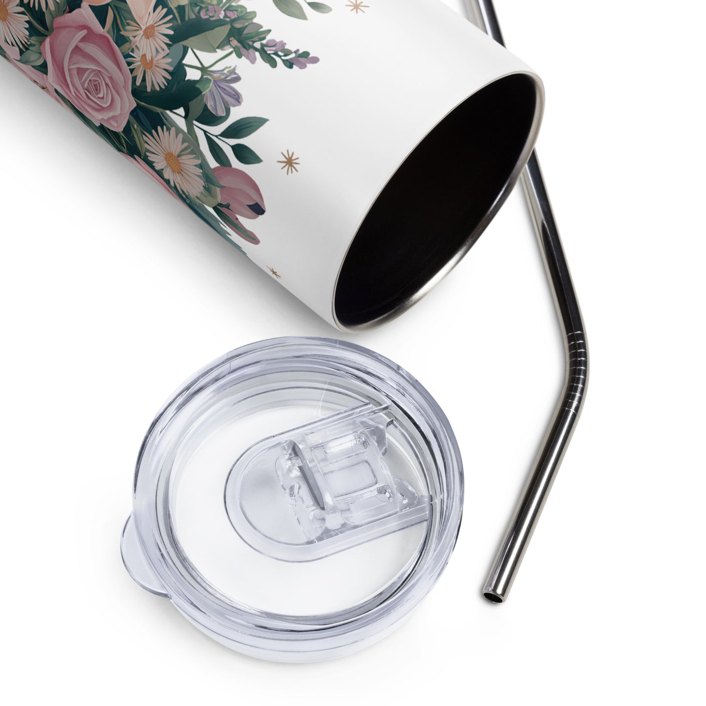 Close-up of a stainless steel tumbler with a wildflower floral print, shown lying on its side with a metal straw and clear plastic lid placed beside it.