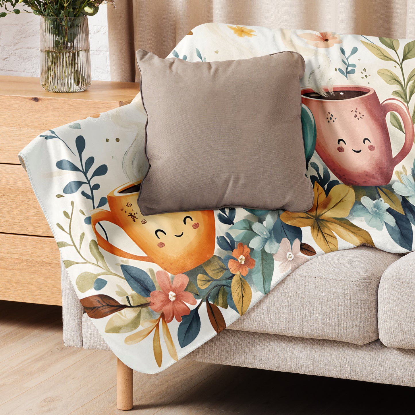 Sherpa blanket featuring smiling coffee cup illustrations and floral pattern draped over a beige armchair