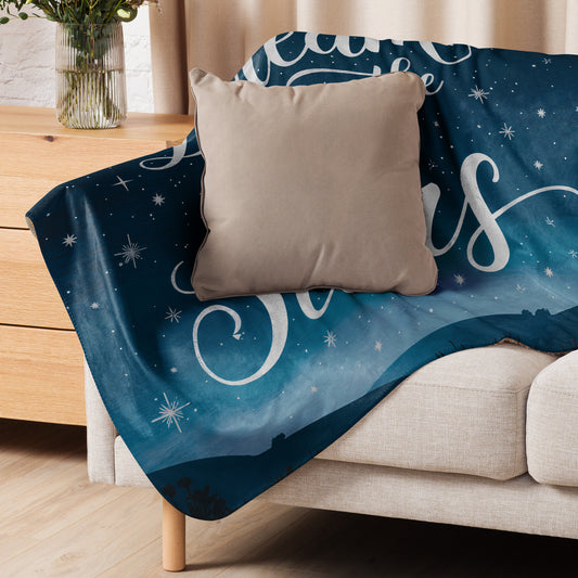 Cozy sherpa blanket with a night sky design draped over a beige sofa, paired with a neutral cushion. Perfect for dreamy evenings and soft home décor.