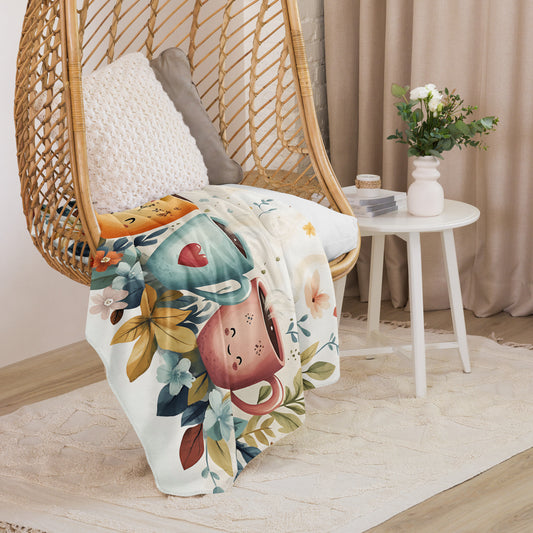 Sherpa blanket featuring smiling coffee cup illustrations and floral pattern draped over a rattan chair - medium size