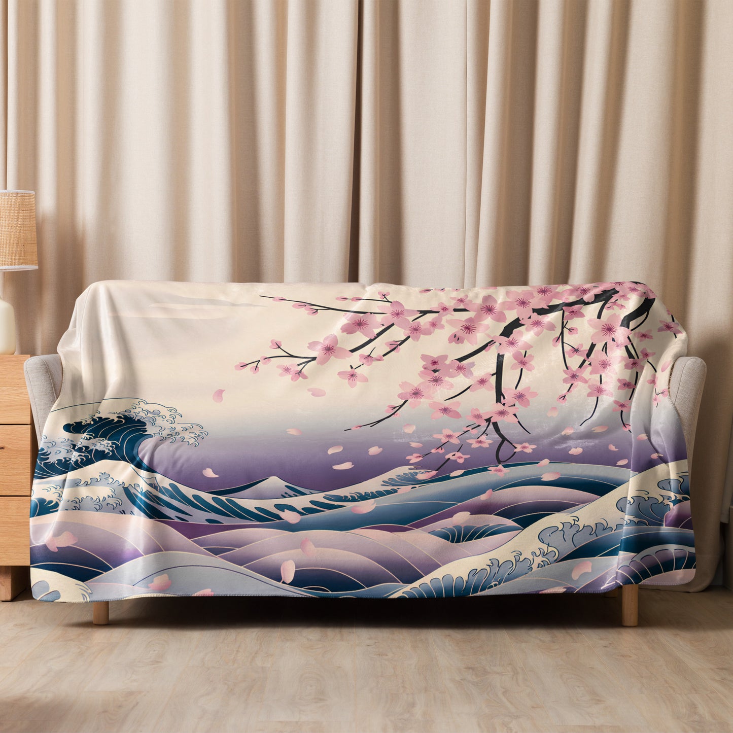 Cherry blossom and wave-patterned sherpa blanket neatly draped over a beige sofa in a cozy living room with soft curtains and a wooden side table.