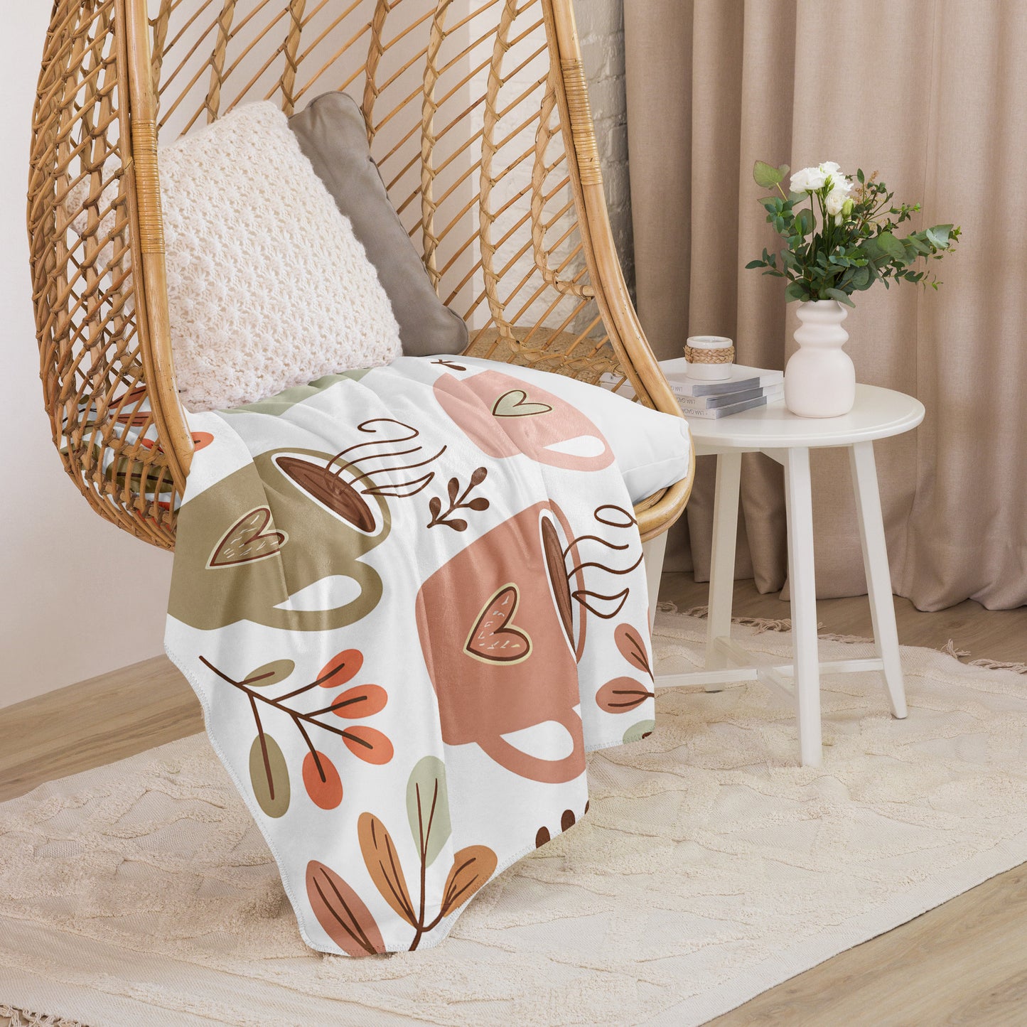 Sherpa blanket in large size with pastel coffee cup and foliage print draped over a rattan chair – cozy and aesthetic gift for coffee-loving moms.