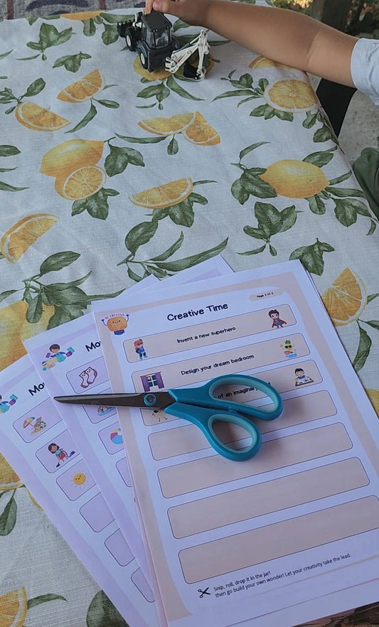 Child playing with a toy tractor next to printed activity sheets on a lemon-patterned tablecloth