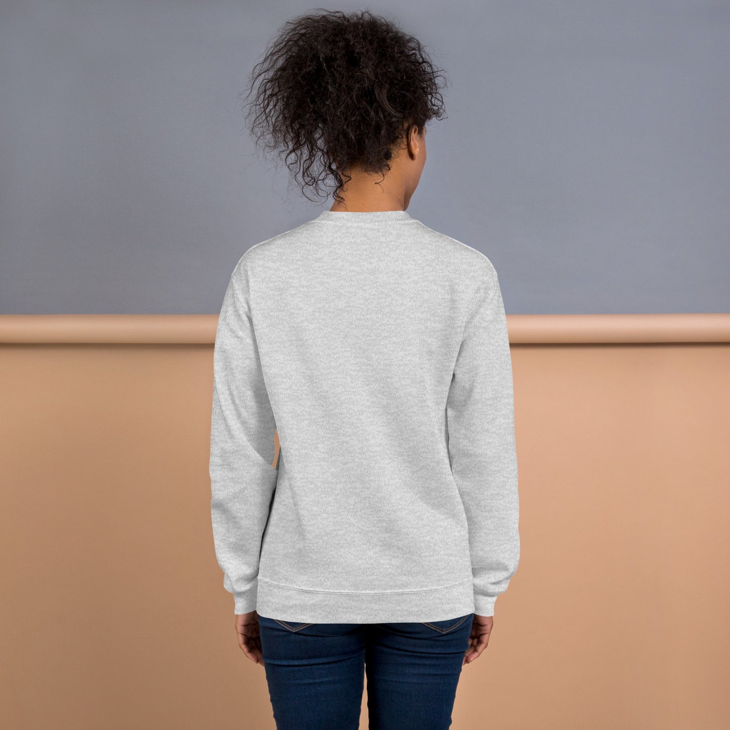 Back view of a woman wearing a light grey crewneck sweatshirt – soft cotton blend, relaxed fit, no print on the back.