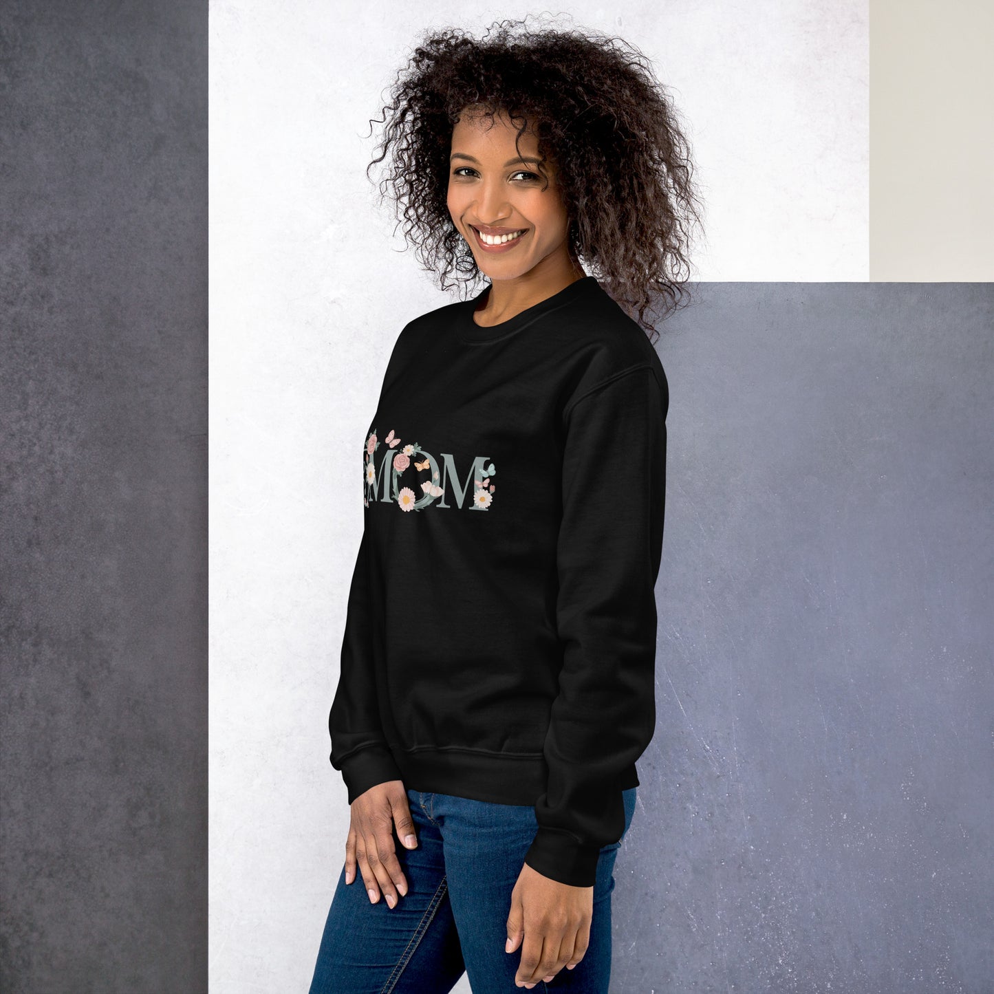 Smiling woman wearing a black floral “MOM” sweatshirt – cozy and stylish gift idea for moms, shown from a side angle.