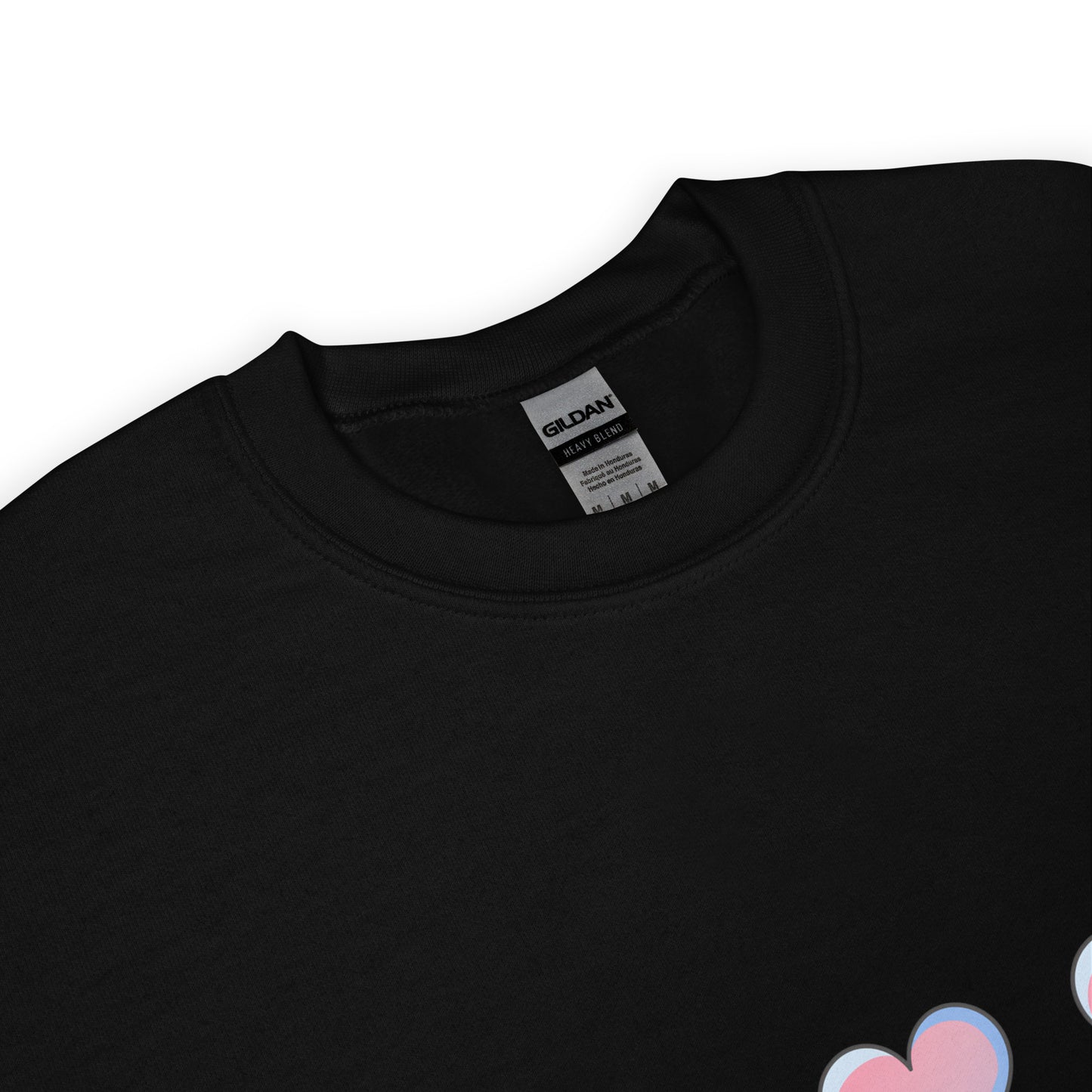Close-up view of a black crewneck sweatshirt with a soft texture, featuring the top part of a pastel heart design near the hem