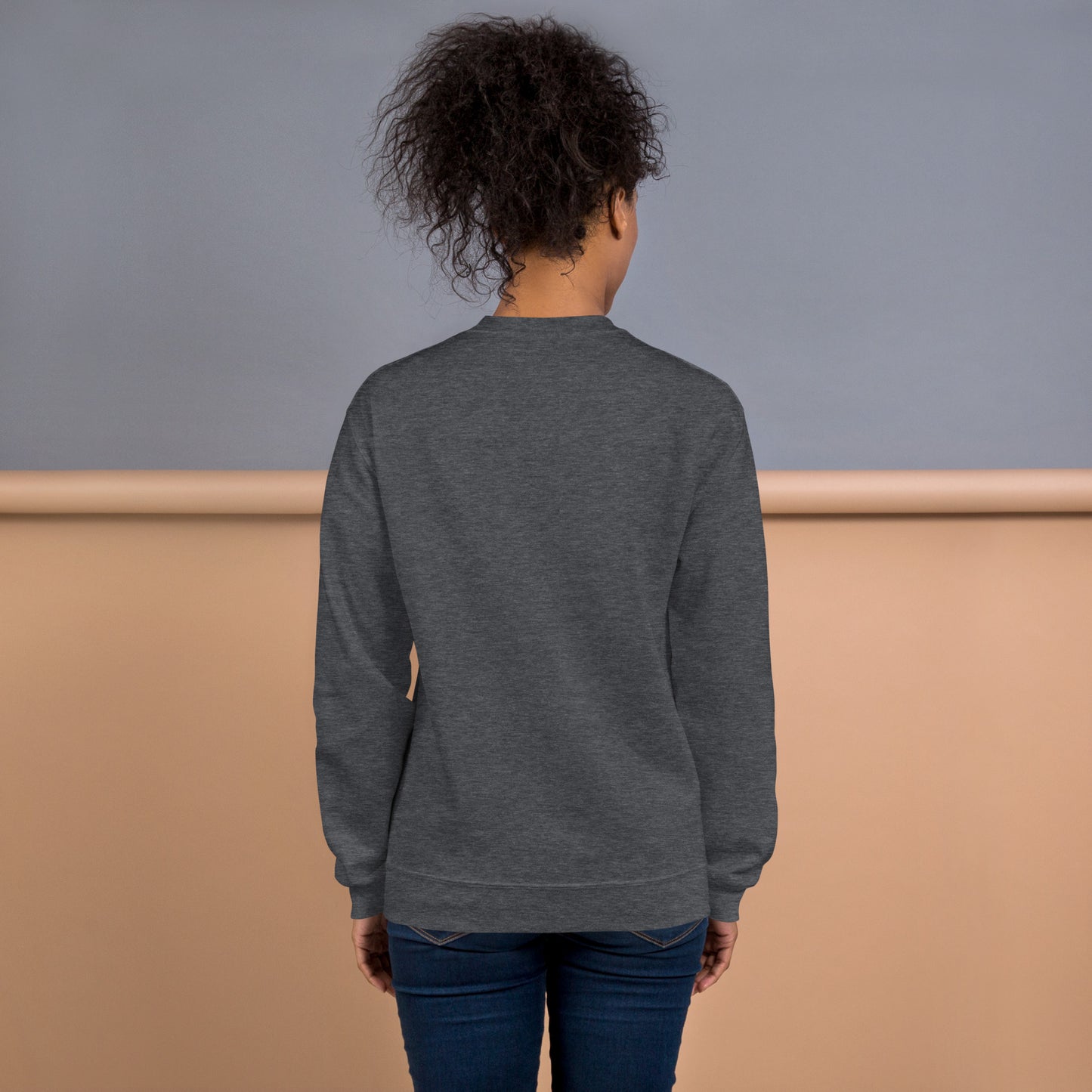 Back view of a woman wearing a dark heather grey crewneck sweatshirt – soft cotton blend, relaxed fit, no print on the back.
