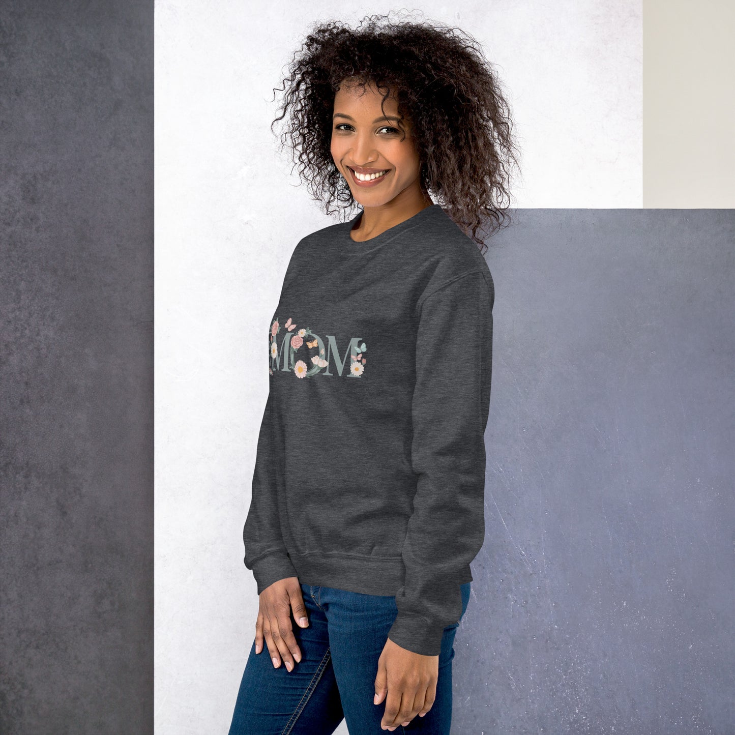 Smiling woman wearing a dark heather floral “MOM” sweatshirt – cozy and stylish gift idea for moms, shown from a side angle.