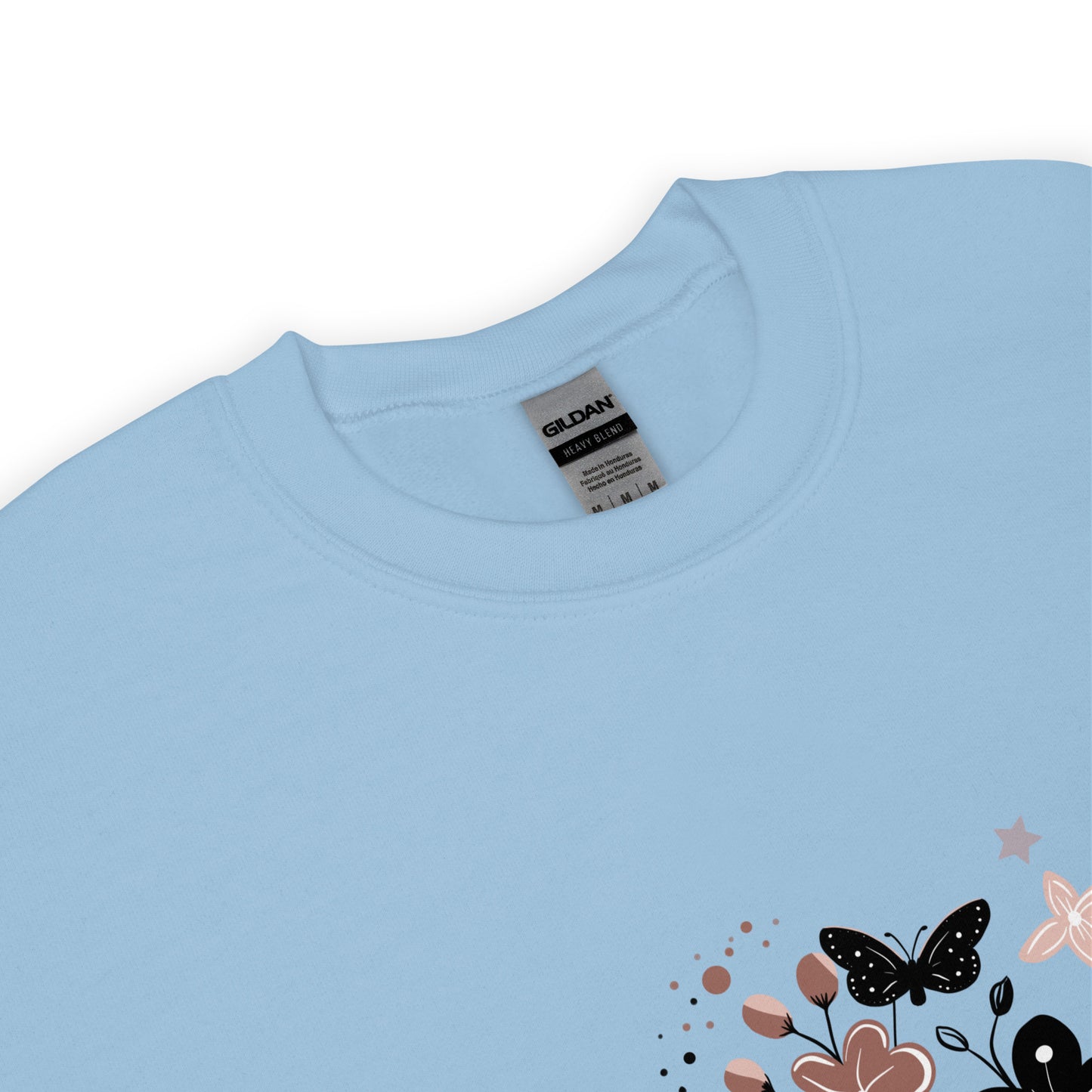 Close-up of a light blue Gildan sweatshirt with a floral and butterfly design printed on the lower corner, showing the collar and fabric texture.