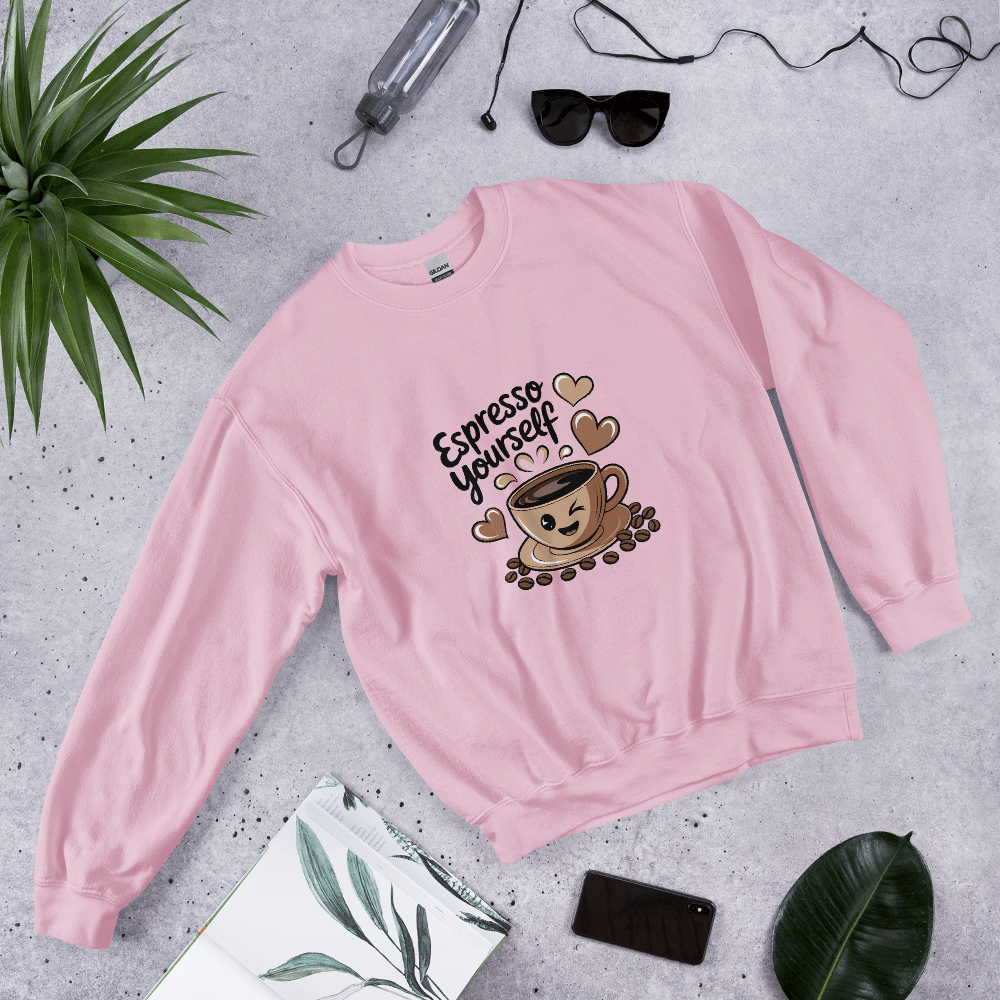 Soft pink “Espresso Yourself” sweatshirt styled flat lay with sunglasses, water bottle, plant, and notebook – cozy coffee lover gift aesthetic.