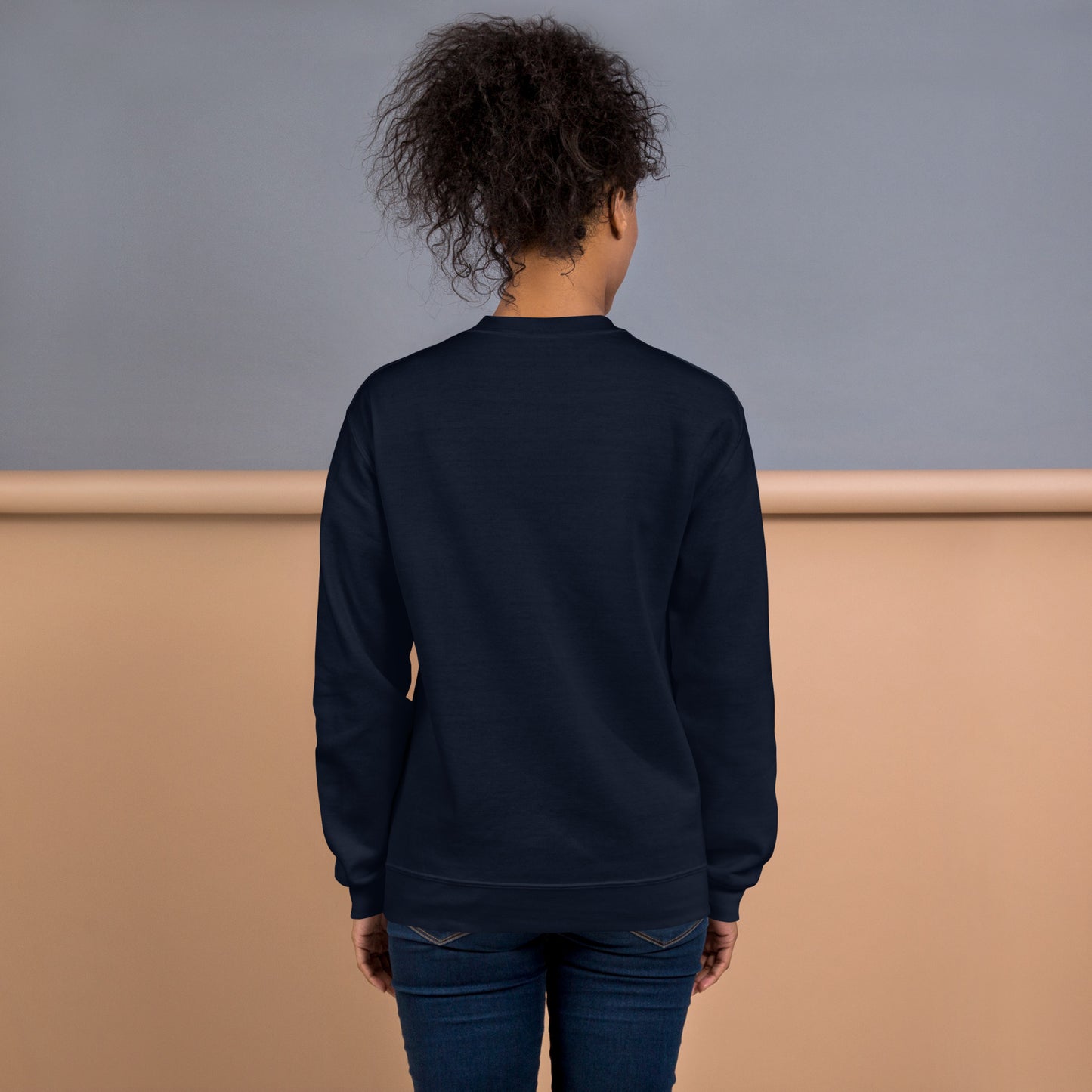 Back view of a woman wearing a navy blue crewneck sweatshirt – soft cotton blend, relaxed fit, no print on the back.