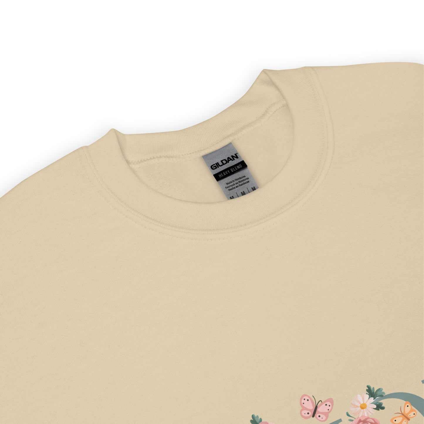 Sand colored crewneck sweatshirt with a close-up of the neckline and a small floral and butterfly design on the lower corner.