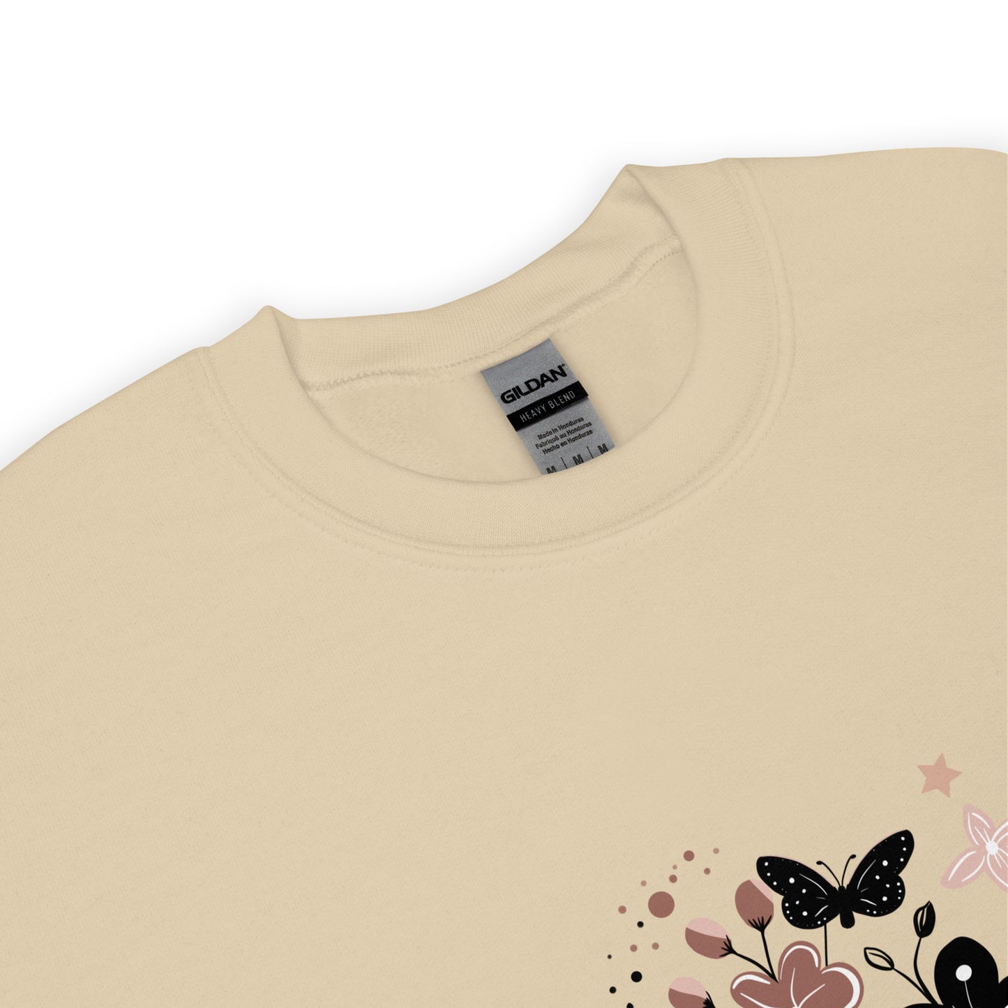 Close-up of a sand Gildan sweatshirt with a floral and butterfly design printed on the lower corner, showing the collar and fabric texture.
