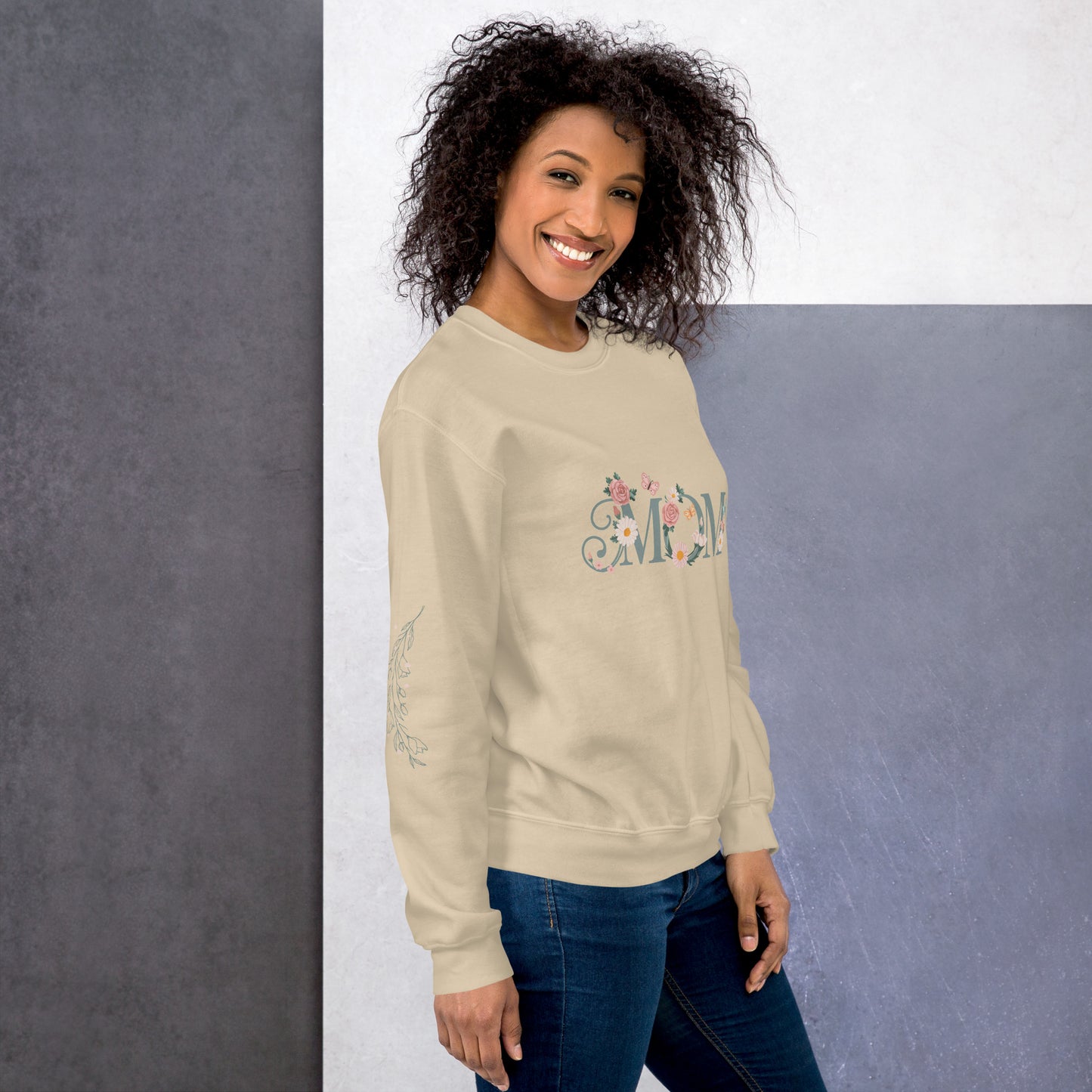 Happy woman wearing a cream sweatshirt with floral “MOM” text and sleeve detail – cozy and stylish sweatshirt for moms, shown from the right side.
