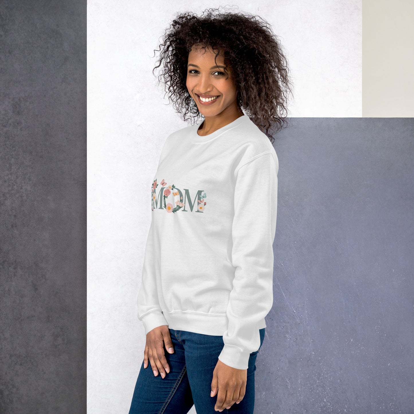 Smiling woman wearing a white floral “MOM” sweatshirt – cozy and stylish gift idea for moms, shown from a side angle.