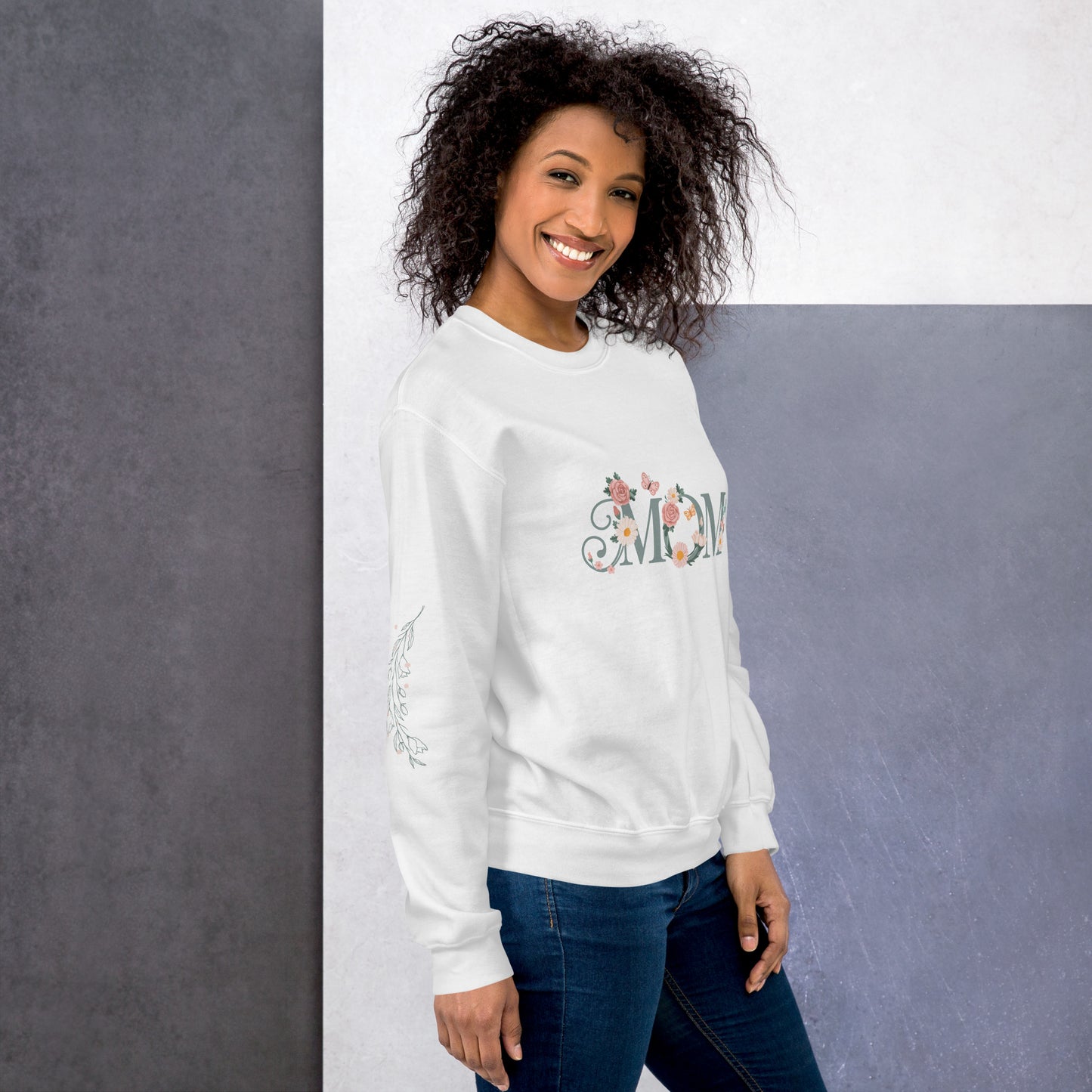 Happy woman wearing a white sweatshirt with floral “MOM” text and sleeve detail – cozy and stylish sweatshirt for moms, shown from the right side.