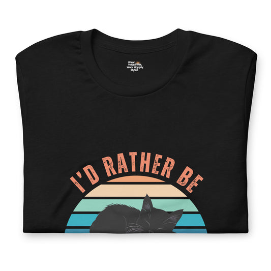 Folded black t-shirt with a retro-style print that says "I’d Rather Be Napping" and features a black cat silhouette against a striped sunset background.