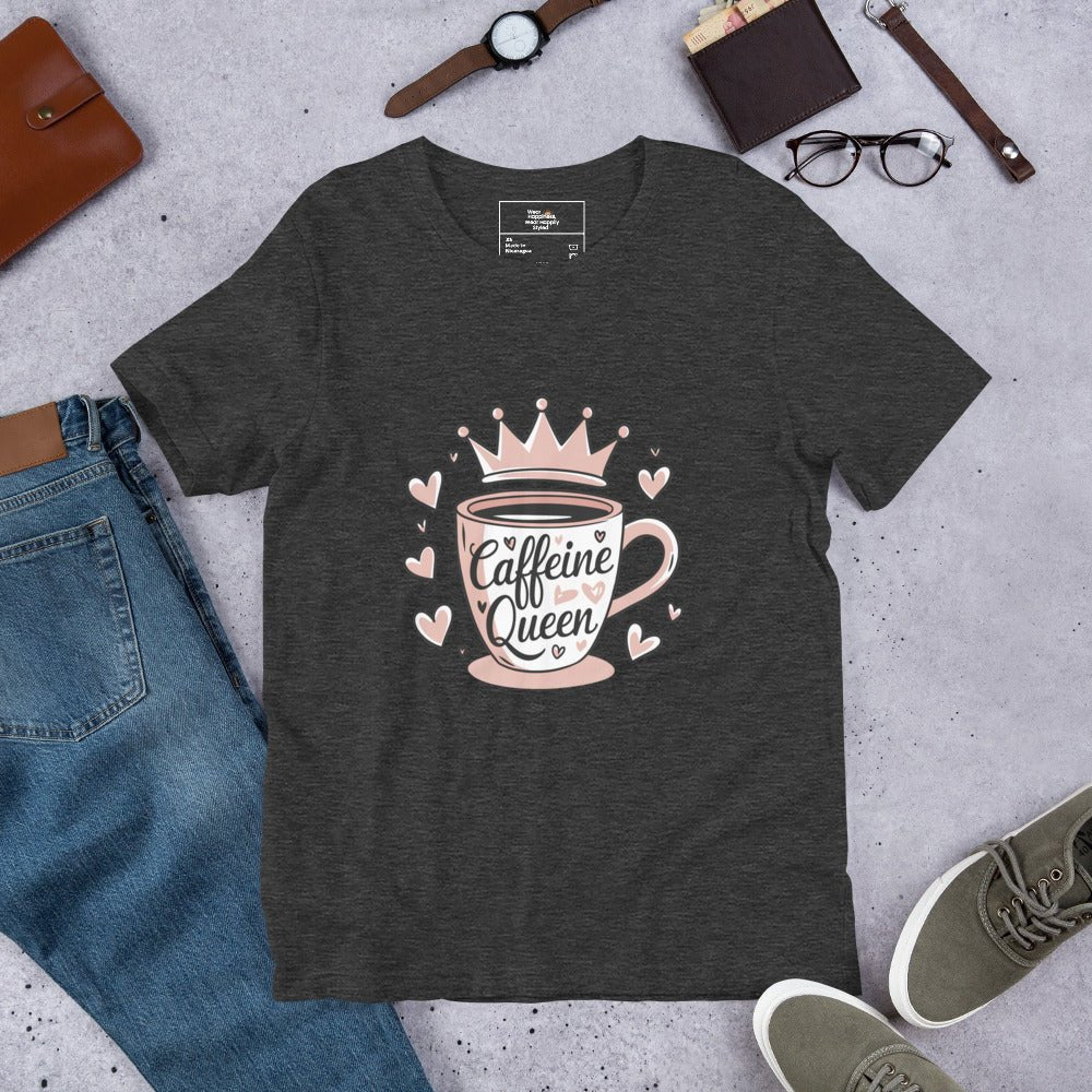 Flat lay of a dark grey heather unisex t-shirt with a pink “Caffeine Queen” coffee cup design, styled with jeans, sneakers, and accessories.