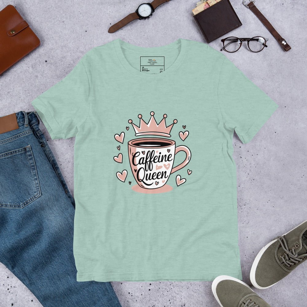 Flat lay of a dusty blue unisex t-shirt with a pink “Caffeine Queen” coffee cup design, styled with jeans, sneakers, and accessories.