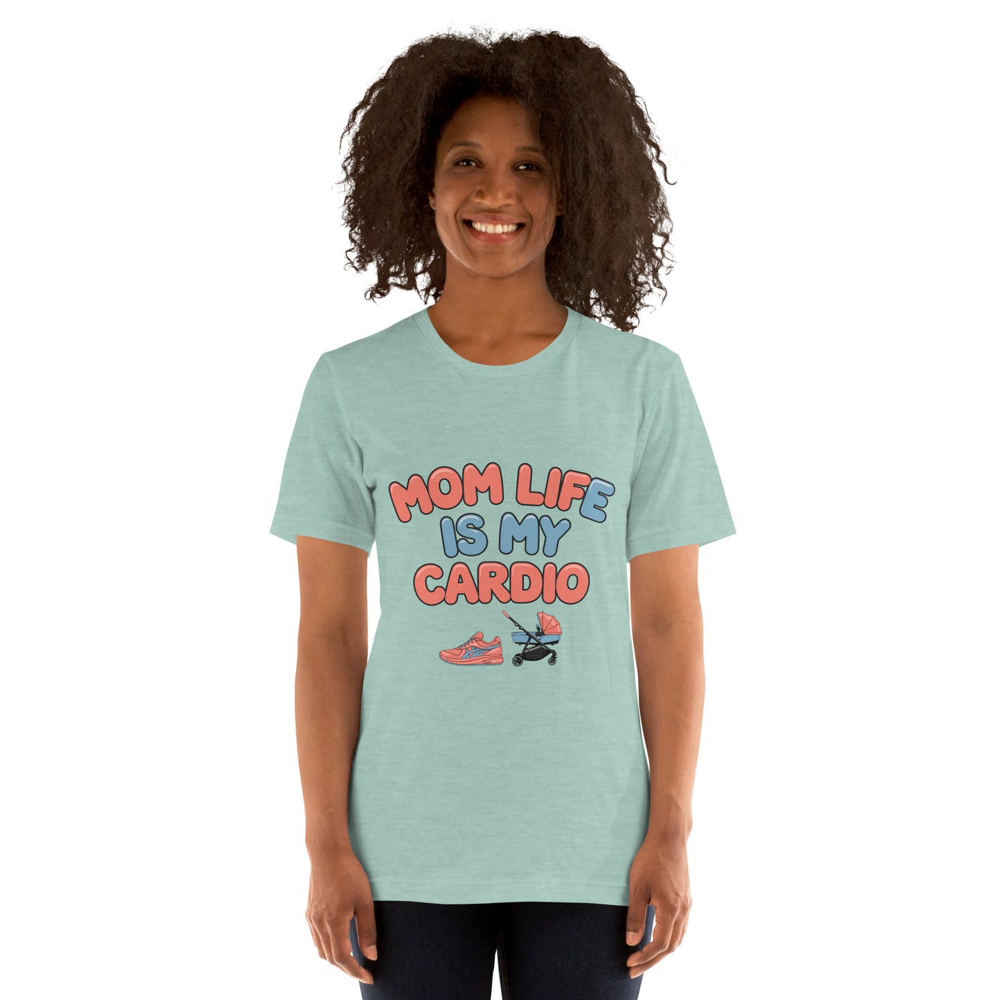 Smiling woman wearing a dusty blue unisex t-shirt with pastel text that says 'Mom Life Is My Cardio' and graphics of sneakers and a pacifier, standing against a white background.