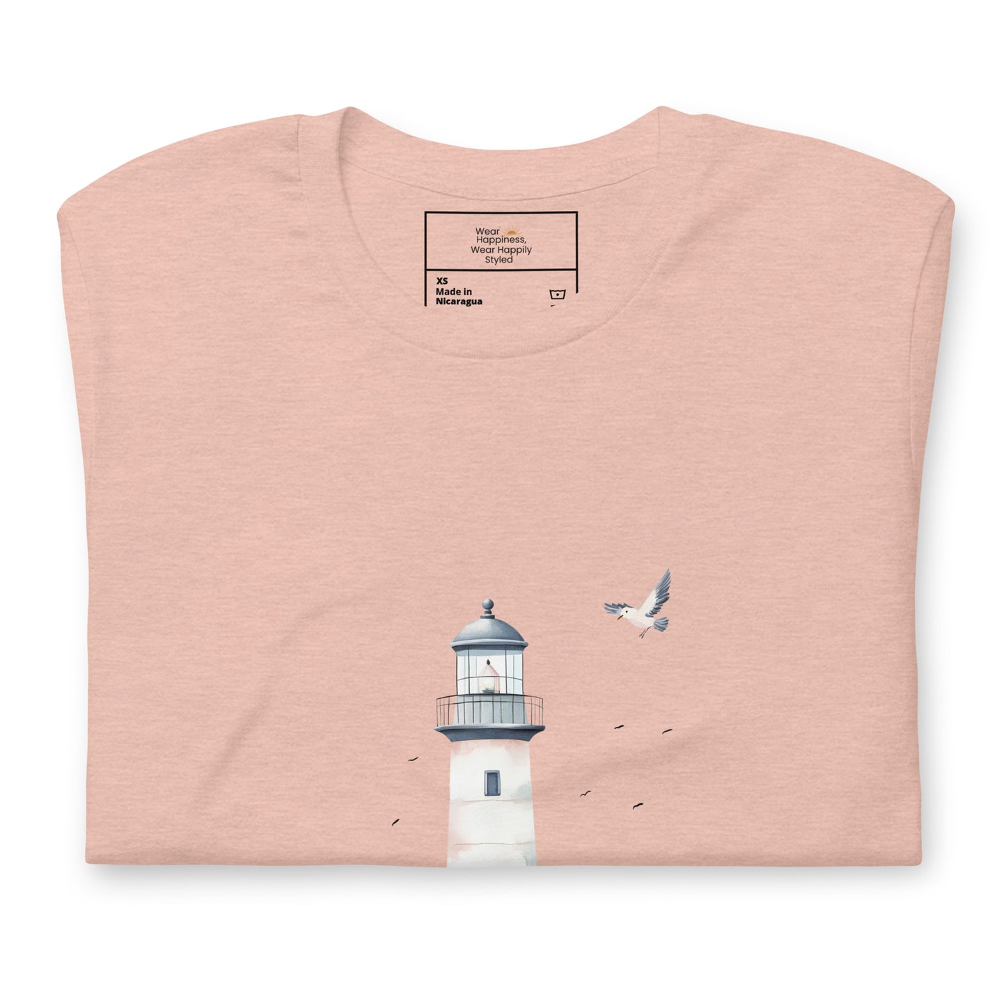 Flat-lay of a folded peach-colored t-shirt featuring a minimal lighthouse and seagull design, styled for a calming, nature-inspired mom aesthetic.