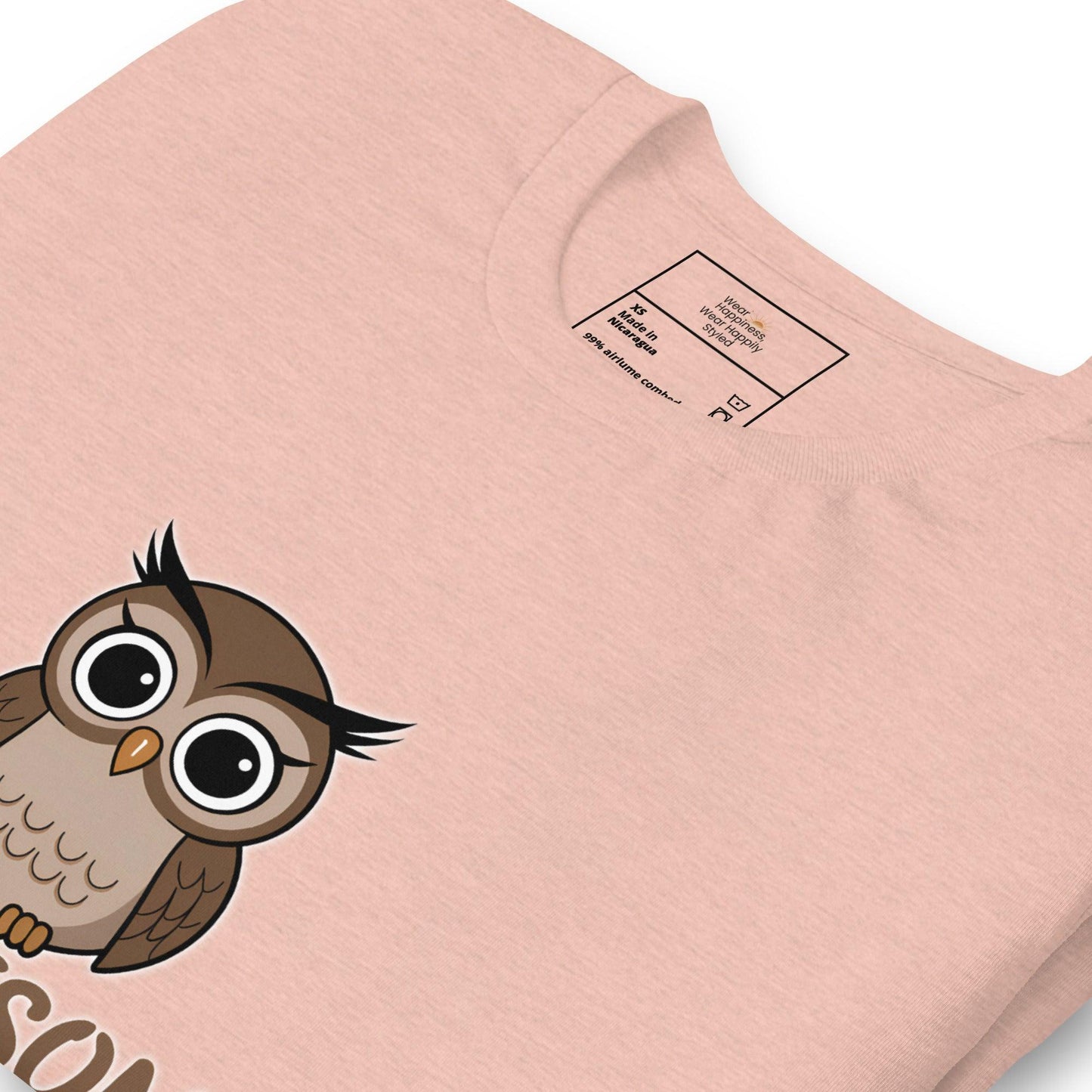 Close-up of a heather peach t-shirt with a cute cartoon owl graphic peeking from the bottom – whimsical and fun design for owl lovers.