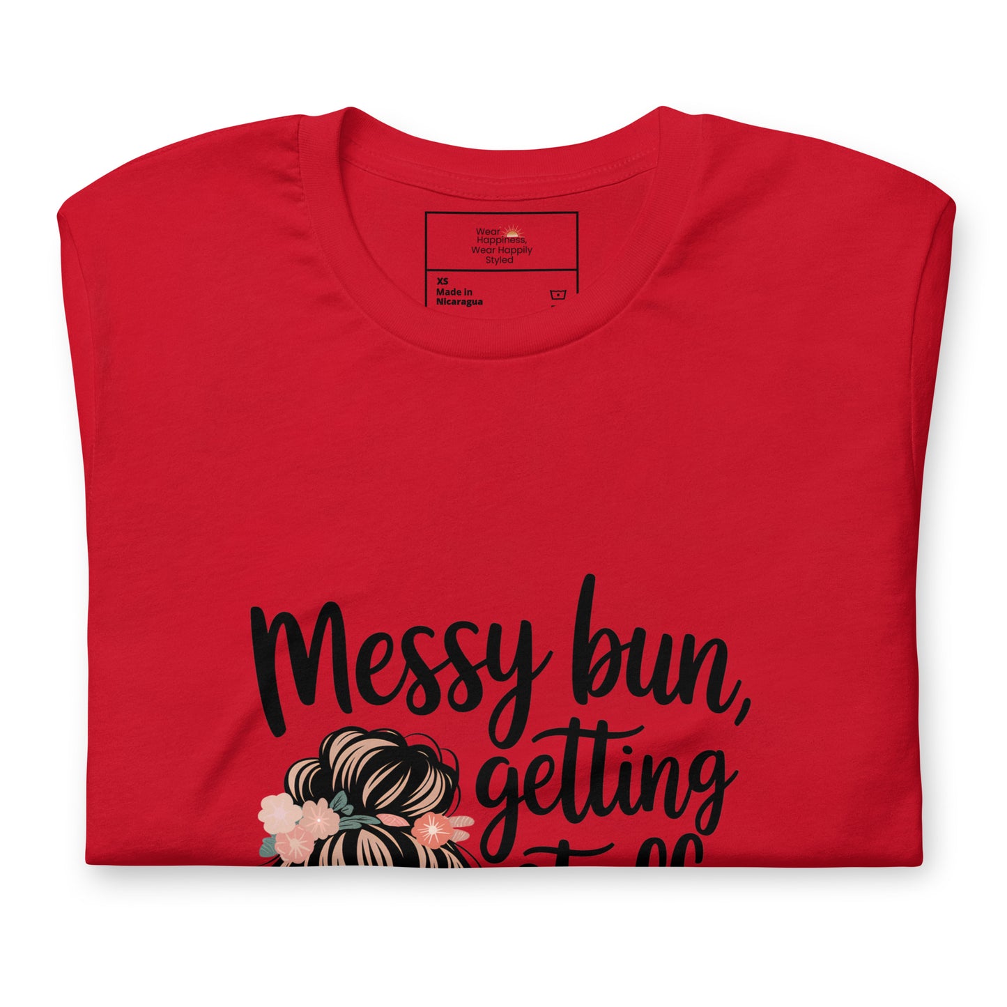 Folded red t-shirt showing black handwritten text 'Messy bun, getting stuff done' with a messy bun illustration and floral details