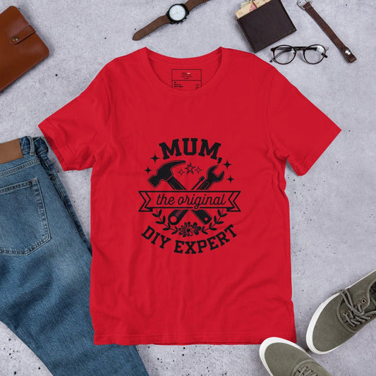 Red t-shirt laid out flat, styled with jeans, sneakers, and accessories, featuring a bold black "MUM – The Original DIY Expert" design — a fun and cheeky gift for crafty moms.