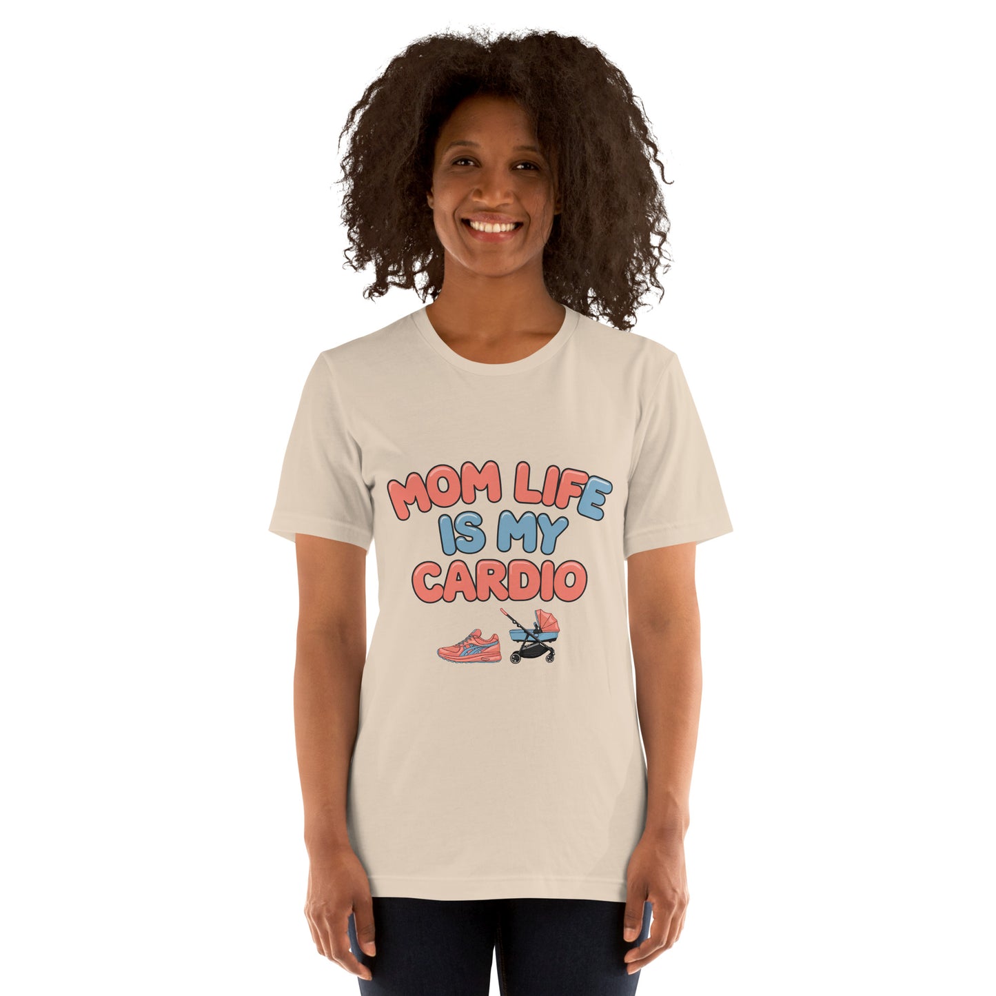 Smiling woman wearing a soft cream unisex t-shirt with pastel text that says 'Mom Life Is My Cardio' and graphics of sneakers and a pacifier, standing against a white background.